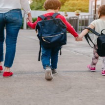 Back to School Safety picture of mom and kids with backpacks crossing the street to get to school